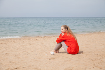blonde woman sitting alone on a sandy beach