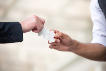 Hands of business people hold paper jigsaw puzzle and solving puzzle together,Business team assembling Jigsaw puzzle,Business group wanting to put pieces of puzzle together.