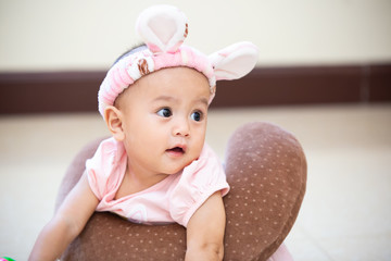 Image of sweet baby girl in a wreath, closeup portrait of cute 5 month-old smiling girl, with pink hat.