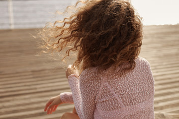 People, travel, holidays, adventure concept. Rear view of young woman with long loose curly hair...