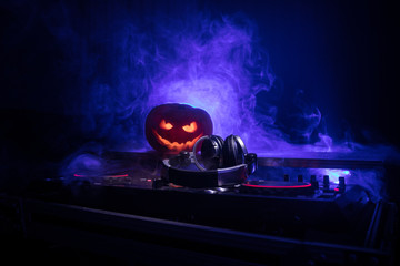 Halloween pumpkin on a dj table with headphones on dark background with copy space. Happy Halloween...