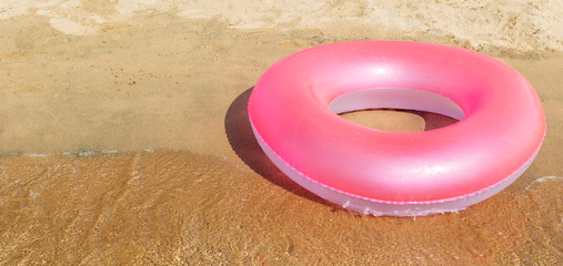 Pink circle float at sea shore.