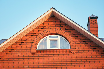 A small window under the roof in a brick cottage