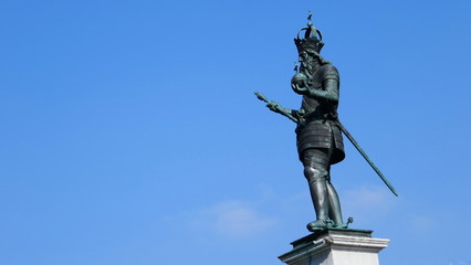 Fototapeta na wymiar Die Statue des Kaisers Karl des Großen steht auf dem Marktbrunnen in Aachen vor blauem Himmel