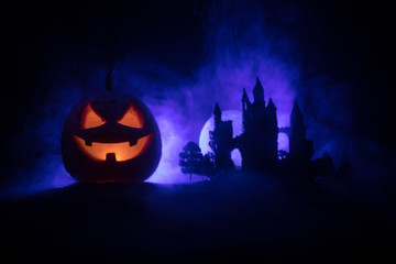 Horror view of Halloween pumpkin with scary smiling face. Head jack lantern with spooky building