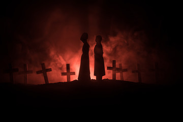 Halloween. Scary zombie bride on a night cemetery holds a pumpkin lantern.