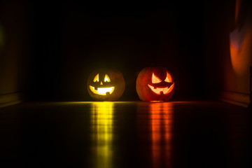 Halloween pumpkin head jack o lantern with glowing candles on background. Pumpkins on wooden floor