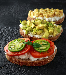 Vegetarian Healthy bread toasts with cottage cheese, heirloom tomatoes, scrambled eggs and avocado