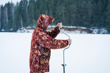 Ice fisherman drill on winter lake