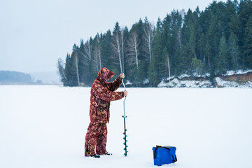 Ice fisherman drill on winter lake