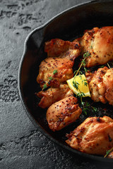 Roasted boneless skinless chicken thighs in lemon and thyme dressing served in vintage cast iron skillet, frying pan