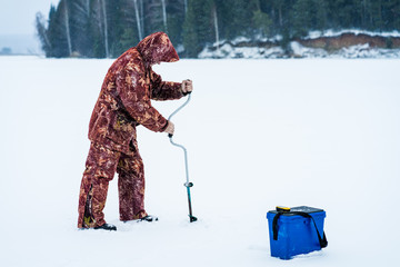 Ice fisherman drill on winter lake