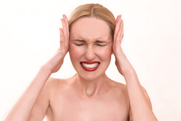 Fototapeta premium Beautiful blonde woman with pretty blue eyes and red lips. A scary female in pain holding her head and screaming in anger with an open mouth on her menstrual cycle period pain