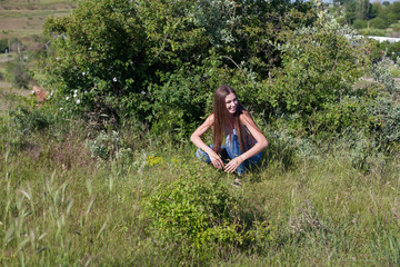 Naklejka na ściany i meble beautiful woman sits in the grass on a walk in the Park