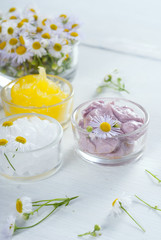 cosmetic product samples with herbal flowers on white wooden table
