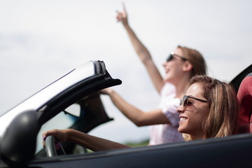 close up.two young women traveling in a convertible car