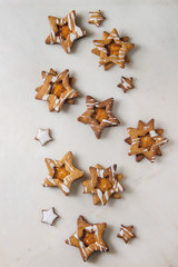 Homemade Christmas star shape sugar caramel cookies with frosting and orange citrus jam over white marble background. Flat lay, space. Sweet xmas or new year gift.