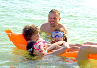 happy family with children is swimming and having fun in the sea on an inflatable mattress. happy friendly family concept