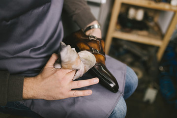 Shoemaker in workshop polishing new handmade beautiful leather shoes.