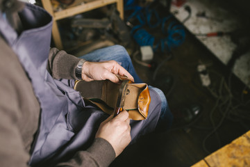 Close up of a male shoemaker working with leather textile at his workshop.