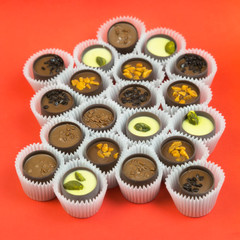 Candy in paper cups on a colored background. Chocolate candies with various fillings in a paper wrapper on a bright background.