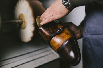 Shoemaker in workshop polishing new handmade beautiful leather shoes.