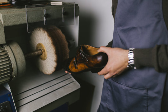 Shoemaker in workshop polishing new handmade beautiful leather shoes.