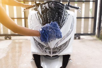 Naklejka premium Myjnia samochodowa, Szczęśliwy człowiek czyszczenia motocykla mycia wody piany w domu