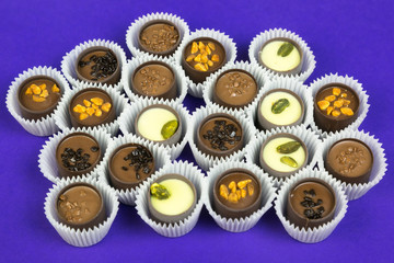Candy in paper cups on a colored background. Chocolate candies with various fillings in a paper...