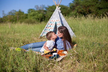 mother and young son eat at a picnic in the forest