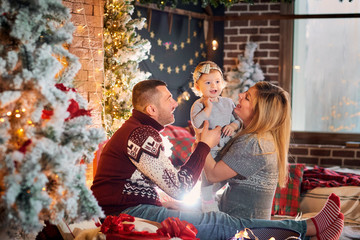 Happy family with a baby in a Santa Claus hat in a Christmas room in Christmas day.