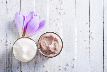 beauty product samples and autumn crocus herbal flower on white wooden table