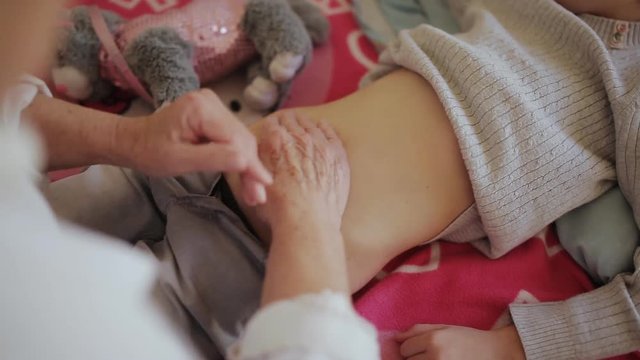 Older female doctor makes poolpatio belly little girl in the hospital, clouse up.