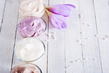 beauty product samples and autumn crocus herbal flower on white wooden table