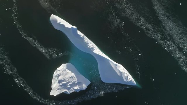Antarctica iceberg aerial drone view flight. Fast top down time lapse shot. Overview the lone snow white ice mountain, among polar winter ocean water. Harsh environment. Beauty of wild untouched