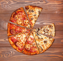 Pizza without one piece, vegetarian mushroom and meat on a wooden table.