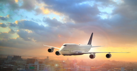 Fototapeta premium Duży biały samolot leci nad chmurami z kolorowym niebem o zachodzie słońca na podróż służbową z samolotem komercyjnym, transportem, importem-eksportem i logistyką, koncepcją podróży