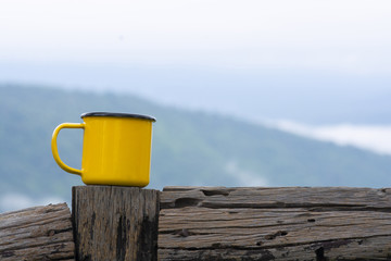 Yellow mug on wooden fence with nature background