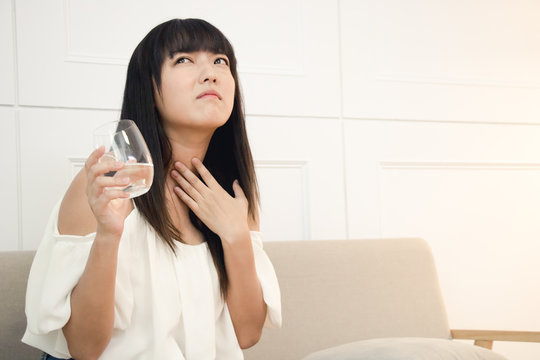 The asian woman cough and has a sore throat. Causes of sore throat include flu or allergy.