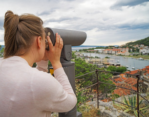 Woman using coin operated panoramic telescope.