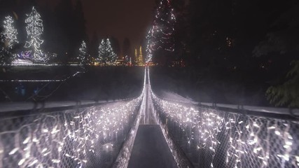 Fast walk through Long Suspension bridge decorated with Christmas lights, Rainy night - Powered by Adobe