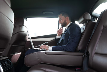 confident businessman sitting on the backseat of a prestigious car