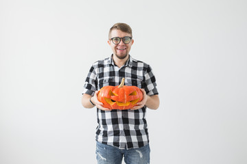 Happy funny man holding a jack o lantern carved halloween pumpkin in light room