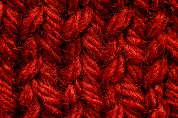 Bright red scarf with knitting needles. On green background. Macro pictures.