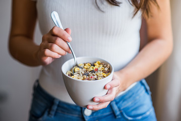 Eating healthy breakfast. Woman holding bowl of cereal. Close-up.