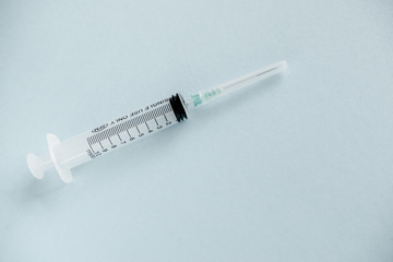 Transparent syringe with a needle, on a background. No liquid in the syringe. Single use only.
