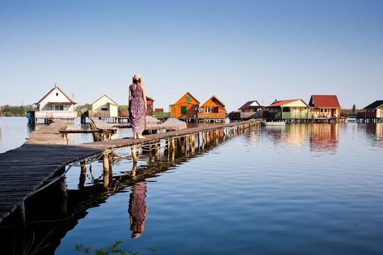 woman walking on the planks at floating village on lake Bokod, Hungary