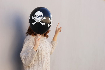 Young pretty woman holding halloween ballon on wall background. Halloween  autumn concept. copy space