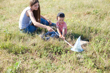mother and young son catch butterflies in the park for a walk