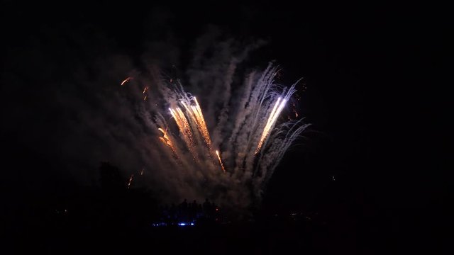 Fireworks fountaining from the ground in gold and then red.